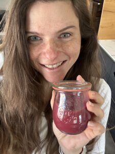 Eine Frau hält ein eingekochtes Weck-Glas selbstgemachtes Rhabarber-Beeren-Apfel-Kompott in der Hand.